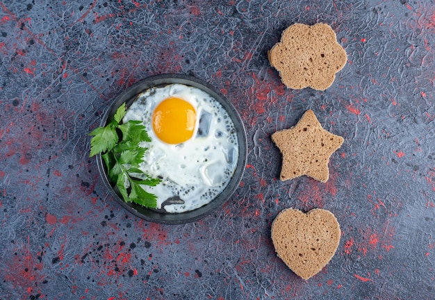 Жареное яйцо с овощами и ломтиками хлеба в форме сердца.