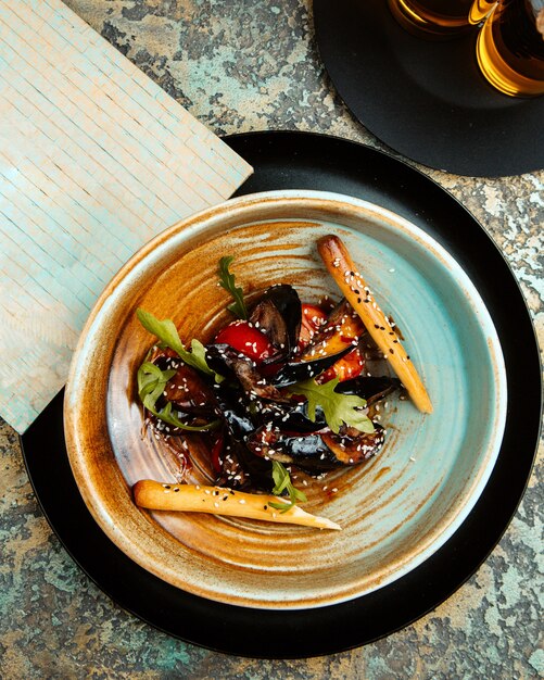  fried eggplant with tomatoes and sesame seeds on a plate