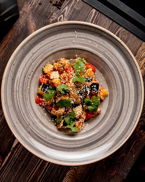 Fried eggplants with tomatoes prepared in sauce and served with cilantro