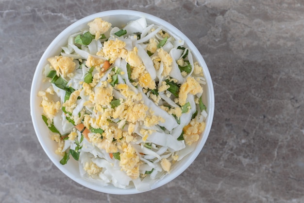 Fried eggs and fresh salad in white bowl.