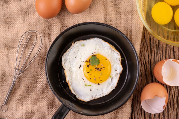 Жареные яйца на сковороде и сырые яйца, натуральные продукты для хорошего здоровья, с высоким содержанием белка