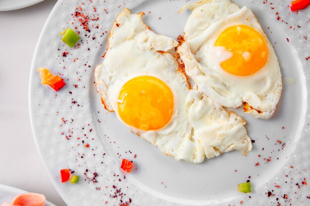 Fried eggs in a plate on a white background. top view.