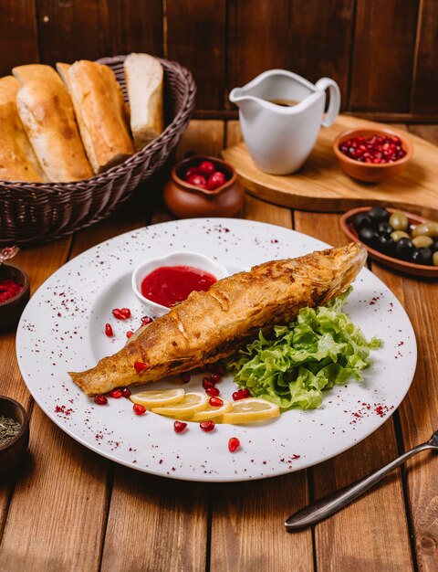 Fried fish plate garnished with lemon lettuce and red sauce