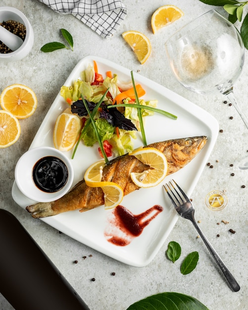 Foto gratuita pesce fritto servito con insalata fresca, limone e narsharab