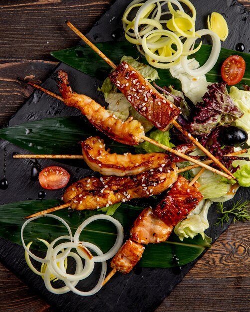 Fried fish and shrimps on sticks served with lettuce tomatoes and onions