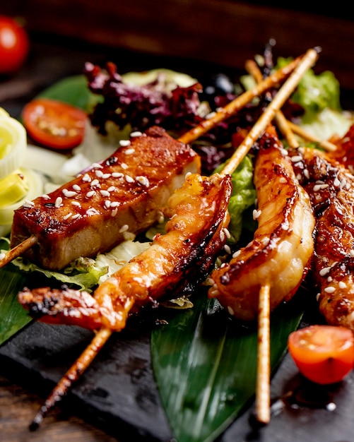 Fried fish and shrimps on sticks served with lettuce tomatoes and onions