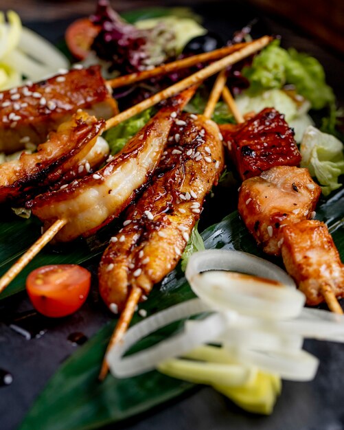 Fried fish and shrimps on sticks served with lettuce tomatoes and onions