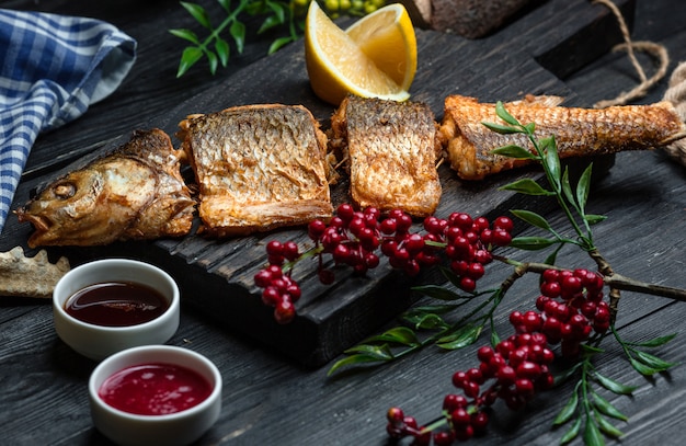 Fried fish with cranberries on wooden board