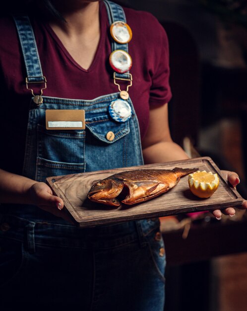 Fried fish with fresh lemon on wooden board