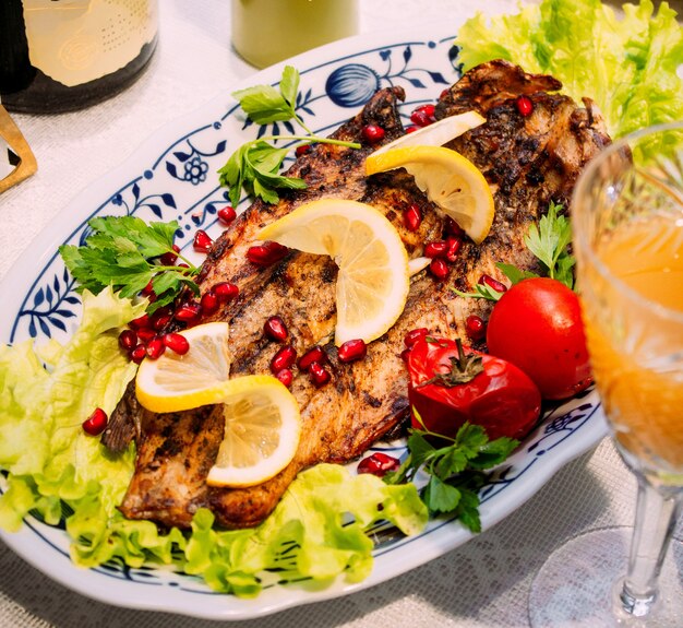 Fried fish with pomegranate and lemon slices