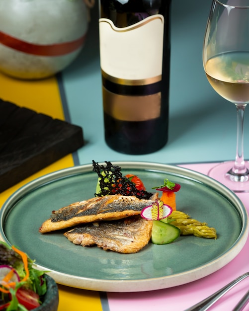 Жареная рыба с овощами и бутылка белого вина