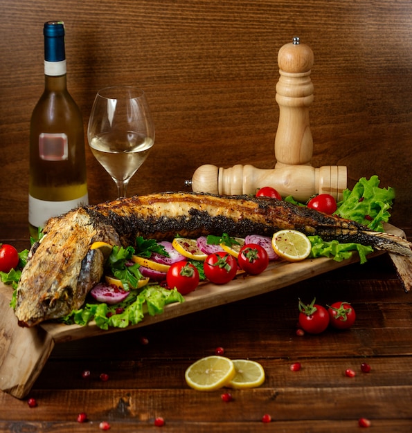 Free photo fried fish with vegetables on wooden board