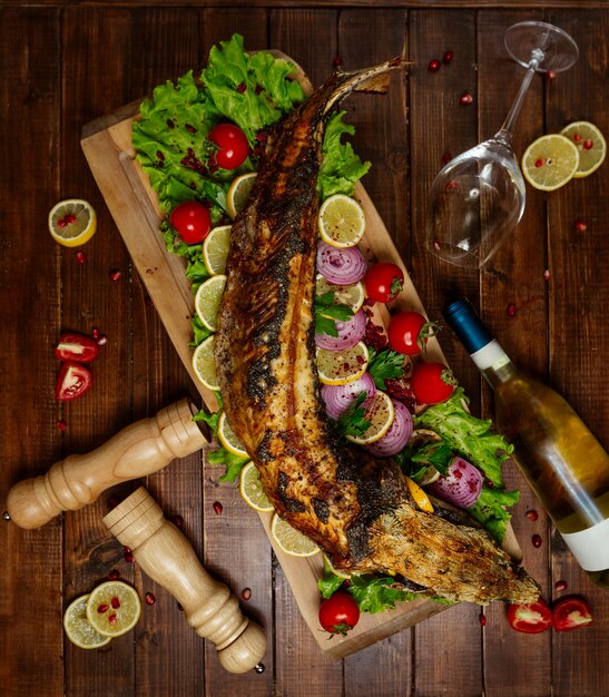 Fried fish with vegetables on wooden board