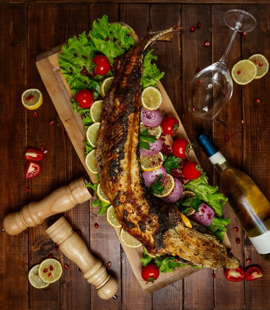 Жареная рыба с овощами на деревянной доске