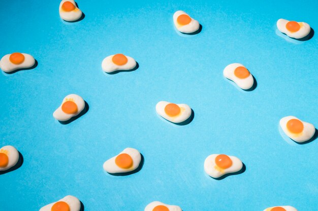 Fried gummy egg candies on blue background