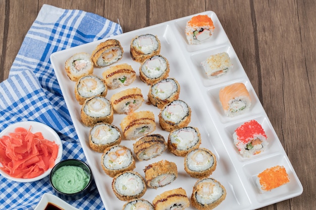 Free photo fried hot sushi rolls with soy sauce, wasabi an ginger on a blue checked towel.