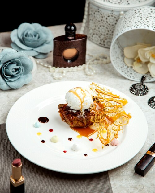 Fried lamb topped with vanilla ice cream placed next to lipstick and perfume