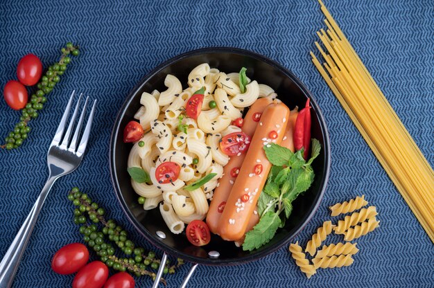 Fried macaroni and sausage in a frying pan.