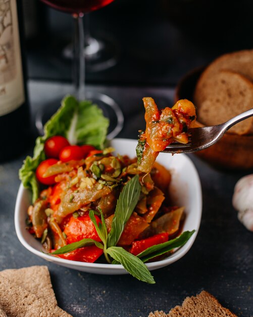 fried meat along with fried vegetables colorful sliced inside white plate along with red wine bread loafs on grey