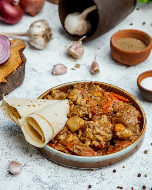 Fried meat, chestnut and onions in a clay promise with pita bread