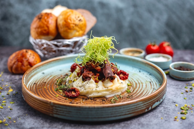 Fried meat placed on mashed potato garnished with shredded bell pepper and thyme