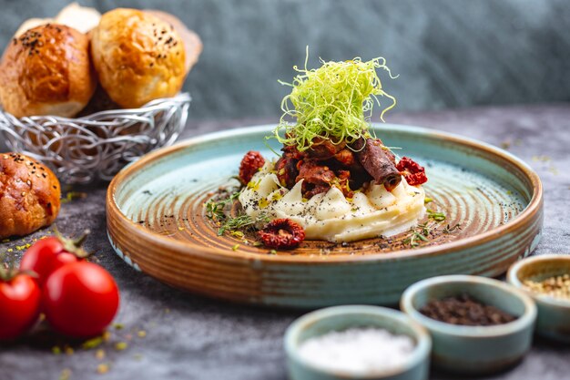 Fried meat placed on mashed potato garnished with shredded bell pepper and thyme