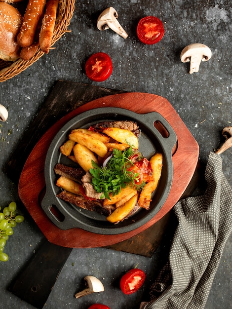 Carne e patate fritte in una padella di alluminio