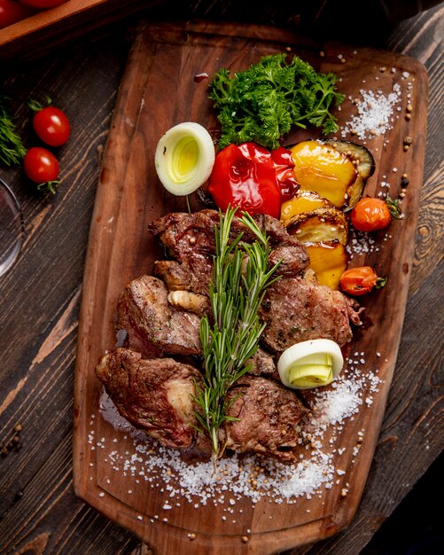 Fried meat served with grilled vegetables onion and  rosemary sprig