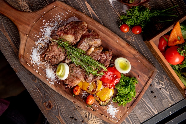 Fried meat served with grilled vegetables onion and  rosemary sprig