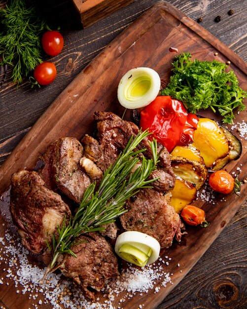 Fried meat served with grilled vegetables onion and  rosemary sprig