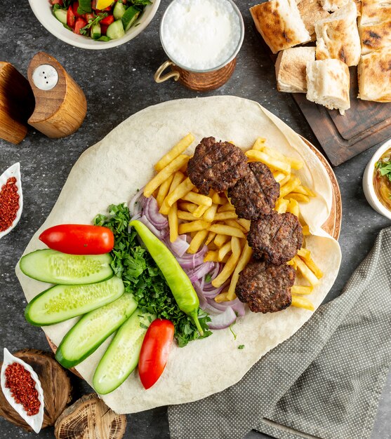 Fried meat served with herbs, vegetables and french fries