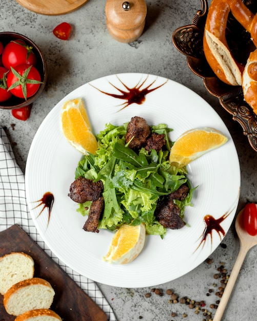 Free photo fried meat with herbs and orange slices