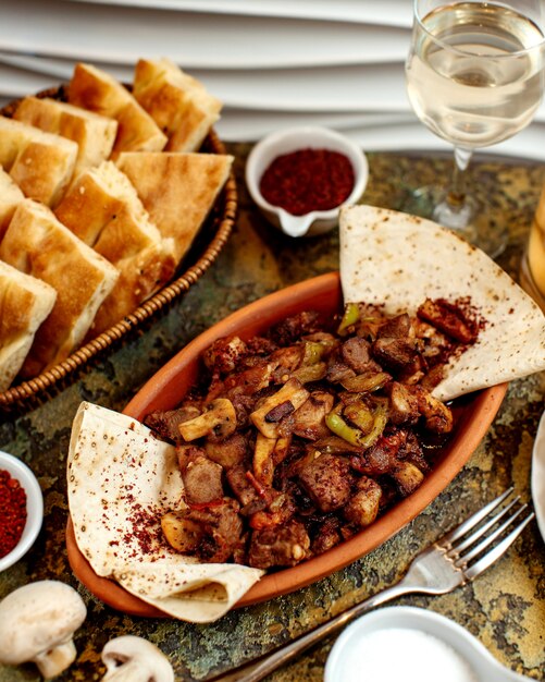 Fried meat with mushrooms and basket with bread