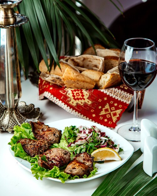 Carne fritta con cipolla e limone e bicchiere di vino rosso