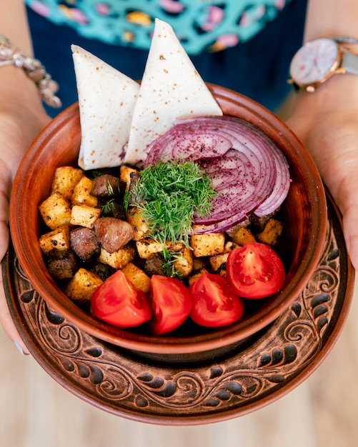 Fried meat with potatoes served with onions tomatoes and greens