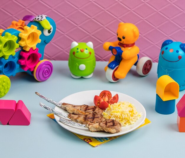 Fried meat with rice and tomato surrounded by toys