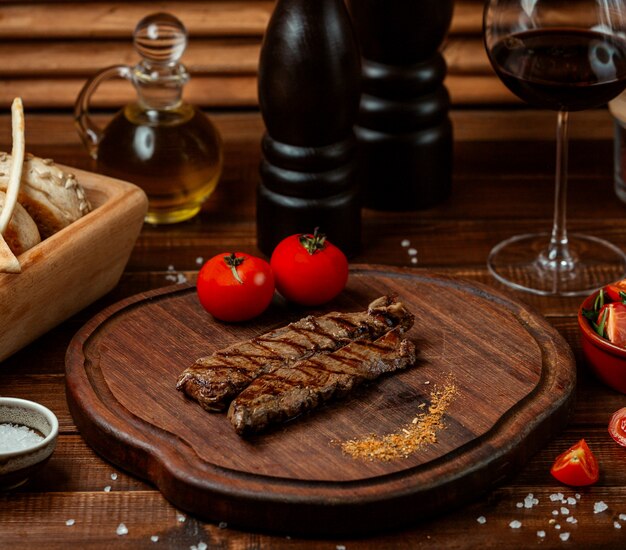 Fried meat with tomato on wooden board