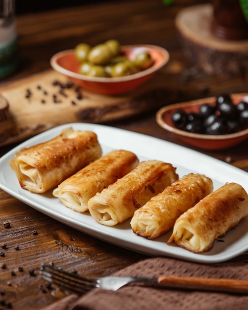 Free photo fried meat wraps as a side dish for dinner with olives