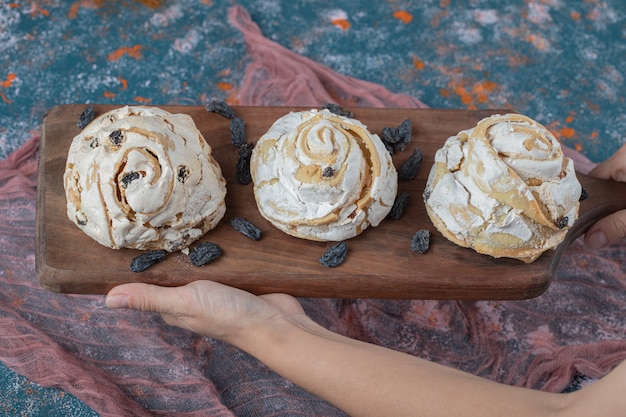 Free photo fried meringue cookie with black raisines on a wooden board.