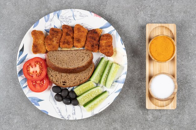 Fried nuggets and fresh vegetables on colorful plate