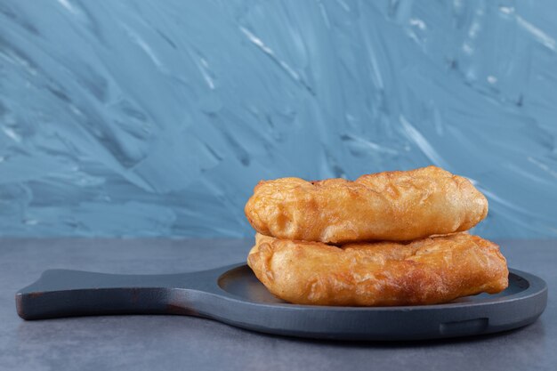 Fried in oil dough in a pan on marble table.