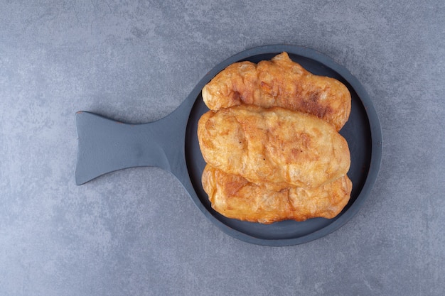 Fried in oil dough in a pan on marble table.