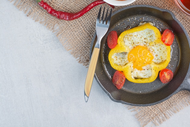 Foto gratuita frittata fritta su peperone giallo sulla padella scura.