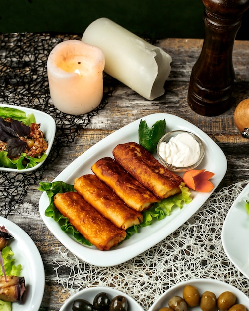 Fried pancakes on lettuce with sour cream