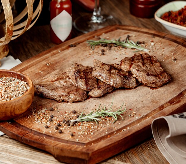 Fried pieces of meat with spices on a wooden board