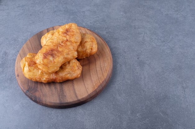 Fried pirozhki on board on marble table.