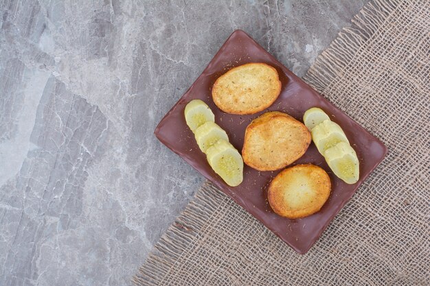 Fried potato slices and pickled cucumbers on plate.