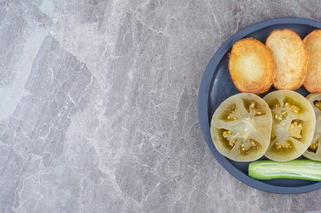 Fried potato slices and pickled tomatoes on plate.