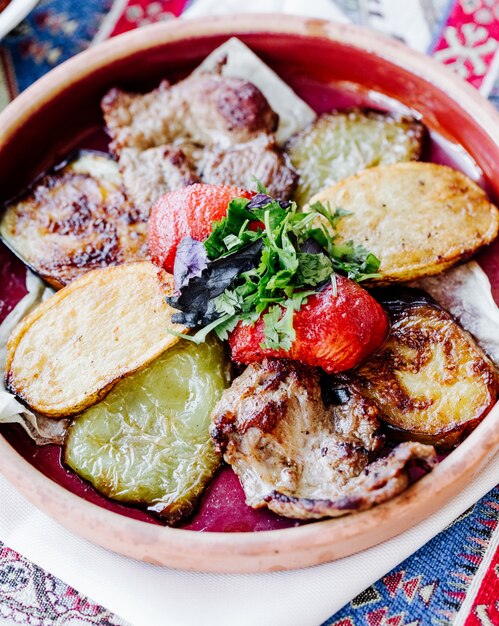 Fried potato slices with meat barbecue , tomato and herbs.