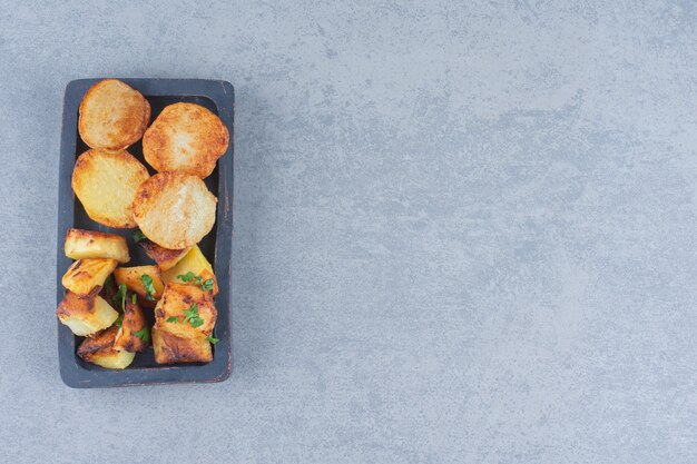 Fried Potato wedges. Fast food on black wooden plate. 